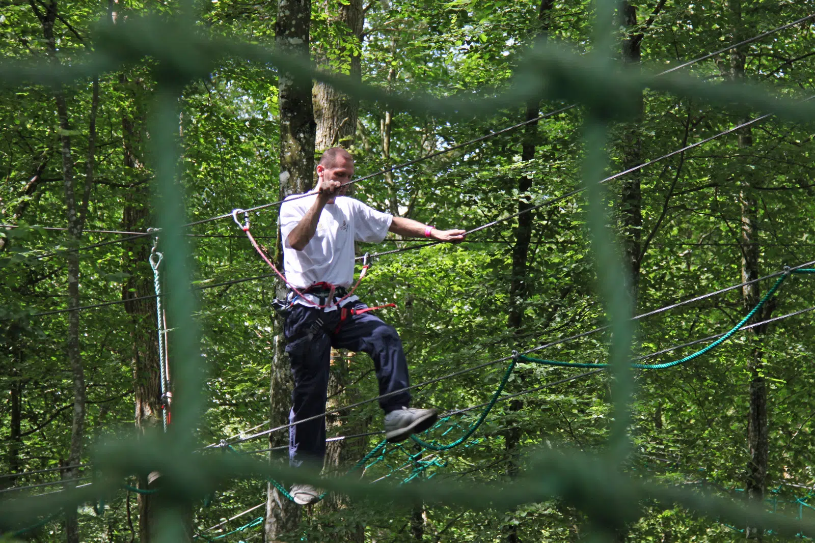 Homme sur parcours d'accrobranche suspendu