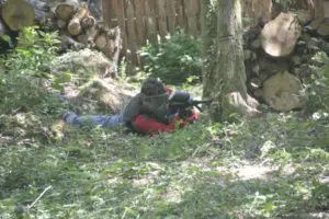 Tireur paintball adulte caché derrière un arbre