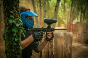 Tireur de paintball de l'équipe bleu planqué derriére un arbre