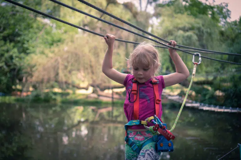 Jeune fille sur parcours d'accrobranche kids